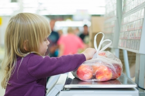 Adorable girl weighting fruits in supermarket